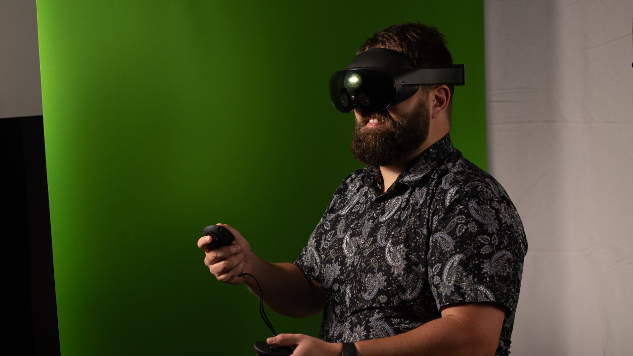 Matthew wearing a VR headset in front of a greenscreen.